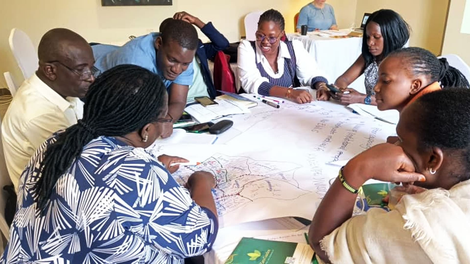 Caritas Kampala programme team gathered around a table planning priority needs and targets
