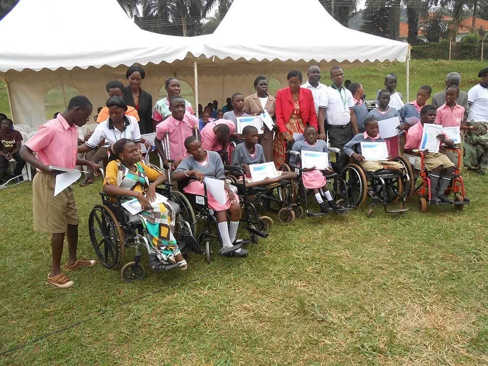 Young people in wheelchairs holding certificates at an event supported by Mapeera Bakateyamba’s Home